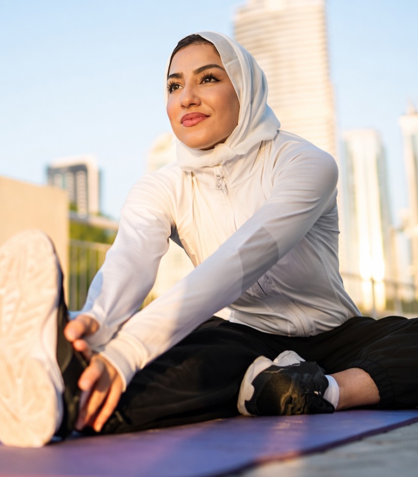 Woman in a hijab stretching outdoors in the city